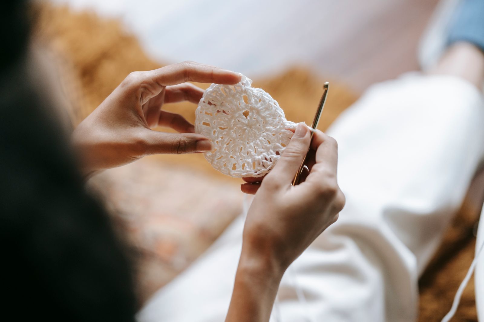 An artisan with a crochet hook and a piece of crocheted fabric