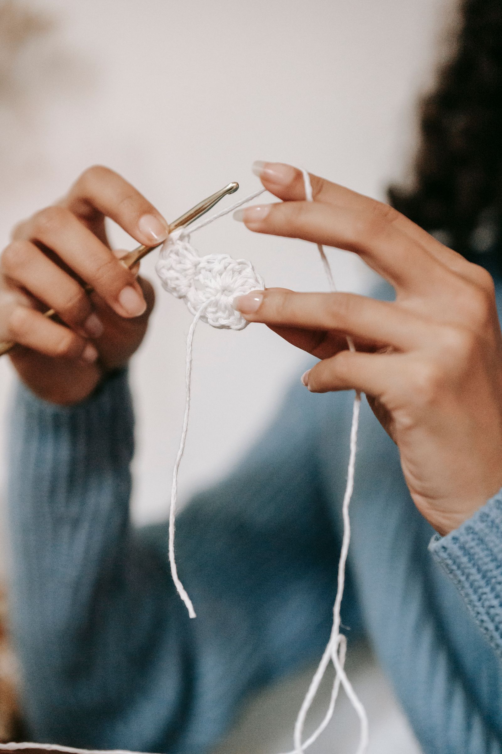 A person crocheting with white yarn, close-up detail