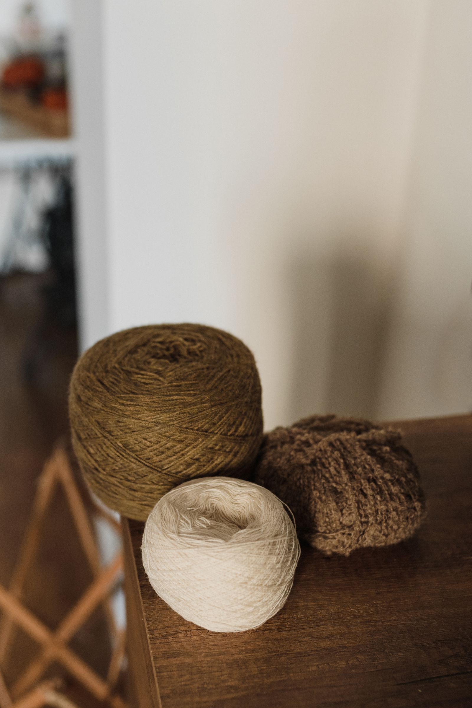 Rolls of natural yarn in earthy tones on a wooden surface